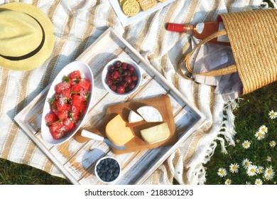 Romantic Picnic With Cheese, Fruit And Wine Outside On A Blanket In Flower Field. 