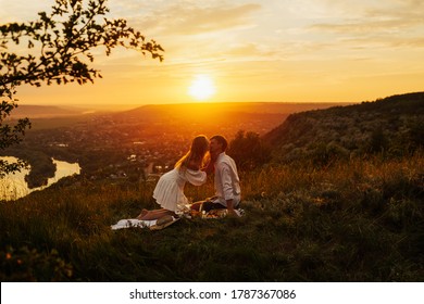 Romantic picnic of couple in love on mountain at gorgeous sunset. They kissing and feeling love. The concept of leisure, privacy, communication and vacation. Copy space.
