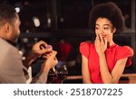 Romantic Proposal Concept. Black Man Proposing To Surprised Woman Offering Engagement Ring, Asking To Marry Him During Date In Restaurant