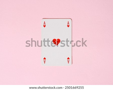 Romantic relationship problems and breakup. Divorce. Ending love. Ace of hearts playing card is lying on a pink surface and showing a broken heart in the middle.