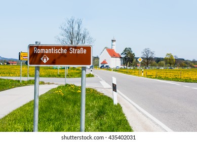 Romantic Road Sign Against St. Coloman Church In Southern Germany 