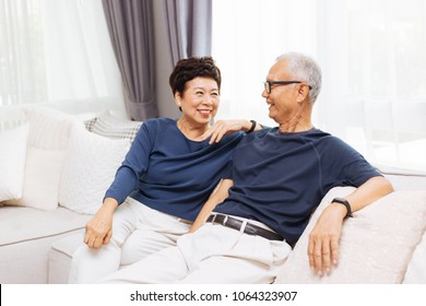 Romantic Senior Asian Couple Laughing And Sitting On Sofa At Home