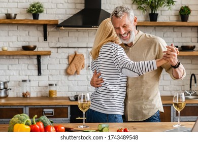 Romantic senior couple having fun while dancing at home - Powered by Shutterstock