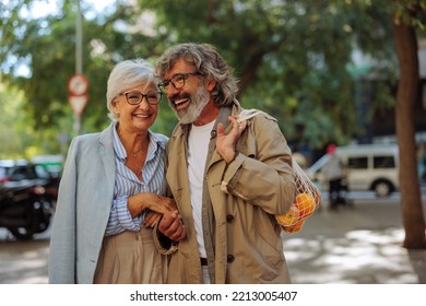 A romantic senior couple is outdoors in the city taking a walk after shopping fruit in the market. - Powered by Shutterstock