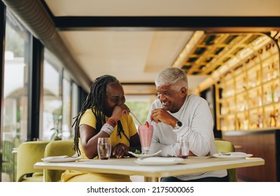 Romantic senior couple sharing a delicious strawberry milkshake in a cafe. Cheerful senior couple having a good time in a restaurant. Happy mature couple enjoying their retirement together. - Powered by Shutterstock