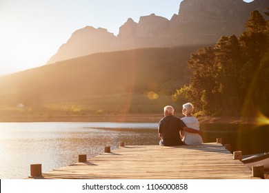 Romantic Senior Couple Sitting On Wooden Jetty By Lake - Shutterstock ID 1106000858