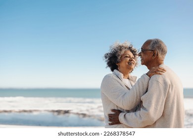 Romantic senior couple smiling happily while standing together on a wooden foot bridge at the beach. Cheerful elderly couple enjoying a refreshing seaside getaway after retirement. - Powered by Shutterstock