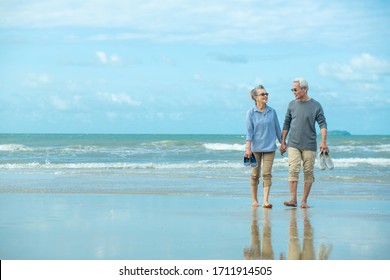 Romantic Senior Couple While Walking Hand In Hands And Talking Together At Beach. Retirement Age Concept And Love.