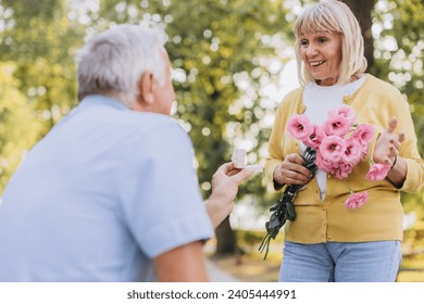 Romantic Senior Gentleman Making Proposal To Happy Excited Lady Outdoors, Grey Haired Man With Engagement Ring Proposing Marriage To Joyful Woman While They Walking In Summer Park - Powered by Shutterstock