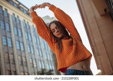 Romantic And Sexy Blonde Young Woman Stretching Arms Up And Closed Eyes. Gorgeous Woman With Slim And Thin Body Posing Outdoor In The Sunset