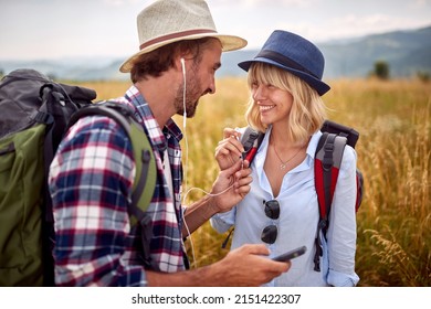 Romantic smiling couple sharing headphones at nature and listening music - Powered by Shutterstock