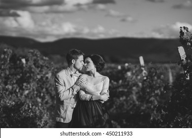 Romantic And Stylish Caucasian Couple Standing In The Beautiful Vineyard At Sunset. Love, Relationships, Romance, Happiness Concept. Black And White Image.