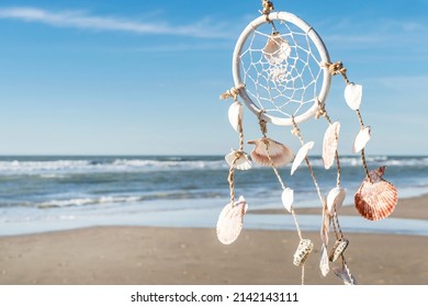 Romantic summer background in hippie style, free space for text. Dreamcatcher in boho style on the background of the sea beach and blue sky. 