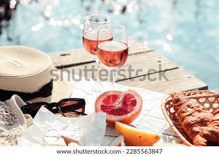 Romantic sunset dinner on the beach. Table honeymoon set for two with luxurious food, glasses of rose wine drinks in a restaurant with sea view. Summer love, romance date on vacation concept.