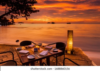 Romantic sunset on the shore of a tropical island. Cafe on the beach. Dinner table