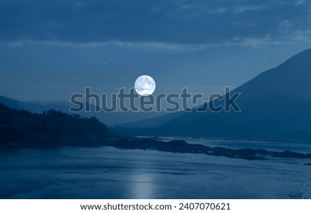 Romantic super white moon over blue mountains and river in the evening of winter