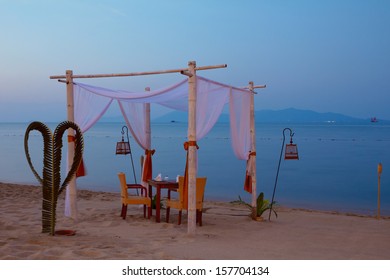 Romantic Table Setting On The Beach At Dusk