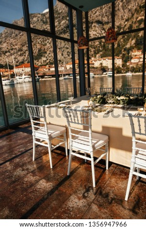 Romantic table setting for wedding reception with sea view through the windows. 