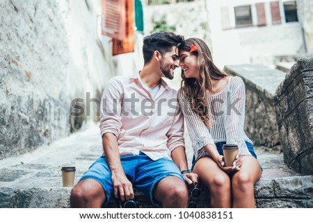 Romantic tourist couple sitting on stairs and drinking coffee