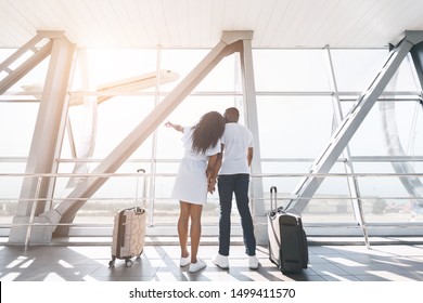 Romantic Travel. Loving Couple Planning Honeymoon, Looking At Window In Airport, Copy Space