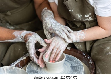 Romantic unusual date in the pottery. Man and woman in love doing clay jar together, holding hands. High quality photo - Powered by Shutterstock