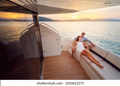 Романтический отдых и роскошные путешествия. Молодая любящая пара сидит на диване на современной палубе яхты. Парус по морю.