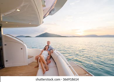 Romantic vacation and luxury travel. Young loving couple sitting on the sofa on the modern yacht deck. Sailing the sea.
