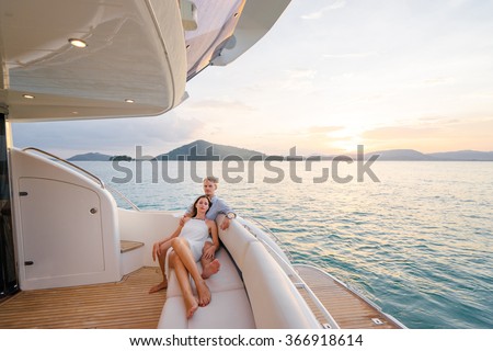 Romantic vacation and luxury travel. Young loving couple sitting on the sofa on the modern yacht deck. Sailing the sea.