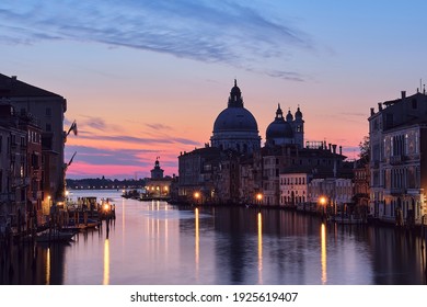 Romantic Venice at night. Cityscape image of Grand Canal in Venice, with Santa Maria della Salute Basilica reflected in calm sea. Lights of passenger boat on the water. - Powered by Shutterstock