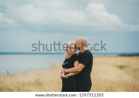 Romantic view of couple in black clothes when they kiss on the edge of the rocky coast of the Baltic sea. Beautiful landscape of sea shore. Closeup portrait