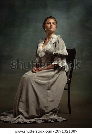 Romantic. Vintage portrait of young beautiful girl in gray dress of medieval style isolated on dark background. Comparison of eras concept, flemish style. Classic art character, old-fashioned.