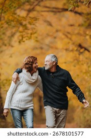 Romantic walk through fall forest by senior couple.