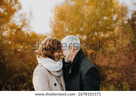 Romantic walk through fall forest by senior couple.