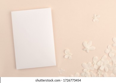  Romantic wedding blank invitation card mock up on soft pink background with small white flowers. Modern neutral minimal feminine stationery presentation design.