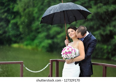 Romantic Wedding Couple Kissing In A Rainy Day