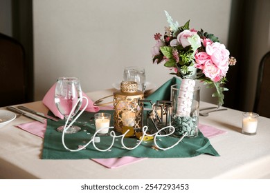 Romantic wedding table decor featuring a floral centerpiece, candles, and a "love" sign, arranged on a pink and green table setting for an elegant and intimate celebration - Powered by Shutterstock