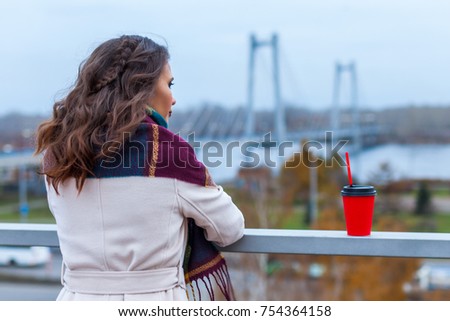 Romantic woman in coat with paper cup of coffee