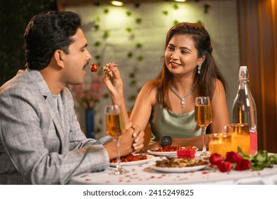 Romantic woman feeding his husband by giving bite during candlelight dinner - concept of romantic date night during valentines day and special occasion - Powered by Shutterstock