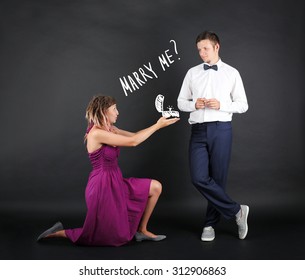 Romantic woman proposing to a man on black background