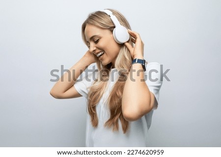 romantic woman sings along to music from headphones among white background