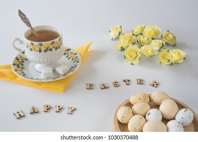 romantic yellow morning scene with cup of tea, roses bowl with Easter eggs, wooden letters, - Powered by Shutterstock