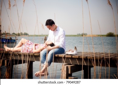 Romantic Young Asian Couple In Love Sitting On Pier.
