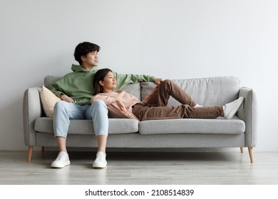 Romantic Young Asian Couple Relaxing On Couch In Living Room, Spending Time Together, Copy Space. Loving Millennial Husband And Wife Resting On Sofa, Chilling On Weekend At Home