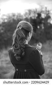 Romantic Young Beautiful Lady Wearing In A Burgundy Coat Looking In The Mirror In Autumn Forest. Victorian Style Vintage. White And Black Photo.