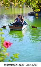 Romantic Young Couple Boating On Calm Lake.