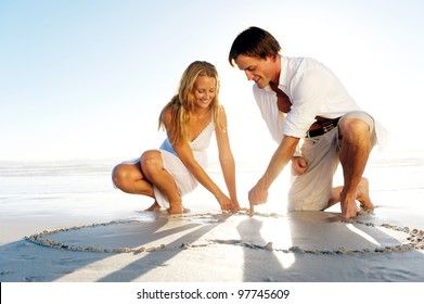 Romantic young couple draw heart shapes in the sand while on honeymoon. summer beach love concept. - Powered by Shutterstock