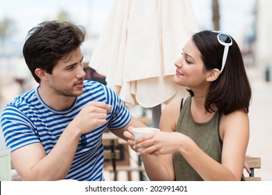 Romantic young couple drinking coffee outdoors seated at a table at a restaurant enjoying a relaxing conversation looking into each others eyes - Powered by Shutterstock