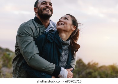Romantic young couple embracing in nature. Happy young man and woman on vacation in countryside.
