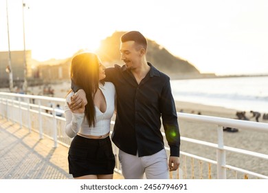 Romantic young couple embracing next to the sea while strolling along a promenade - Powered by Shutterstock