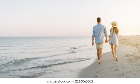 Romantic young couple in love walking together at sunset along a mediterranean beach. Summer holidays in a warm country. Happy married couple on vacation. without a face. Banner. copy space. - Powered by Shutterstock